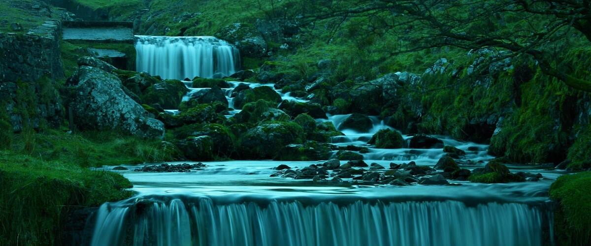 A waterfall cascading over rocks in a lush green valley.