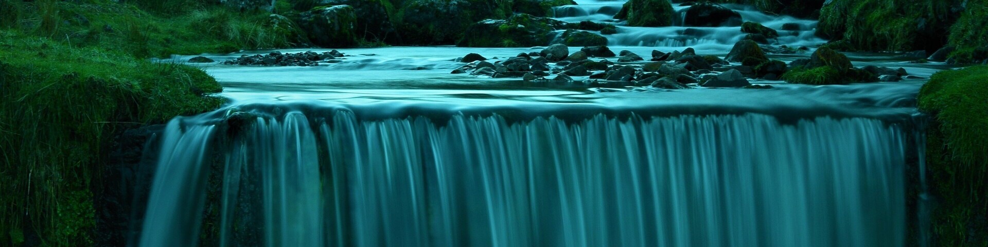 A waterfall cascading over rocks in a lush green valley.