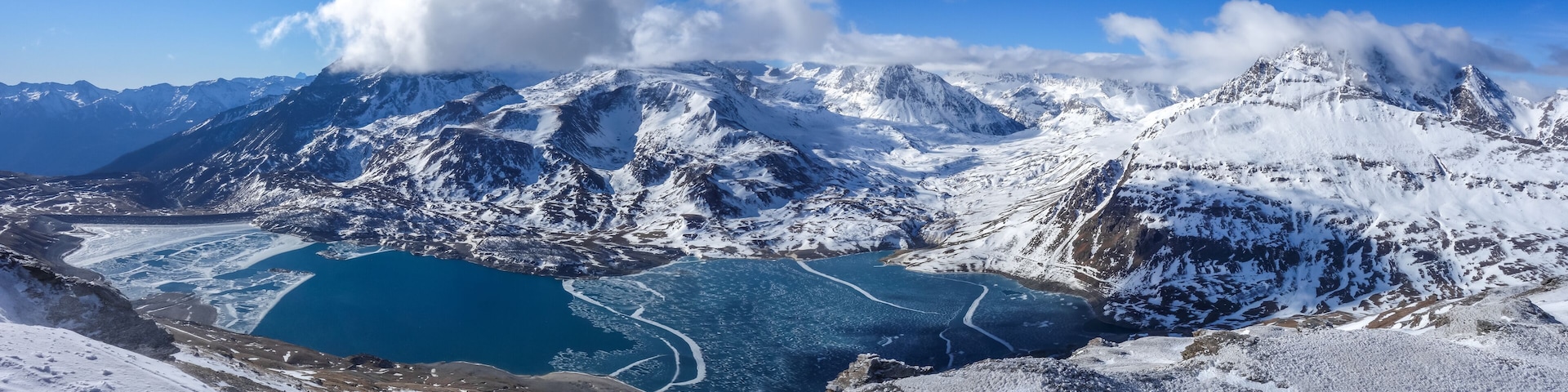 Une chaßne de montagnes enneigées avec un lac glaciaire.
