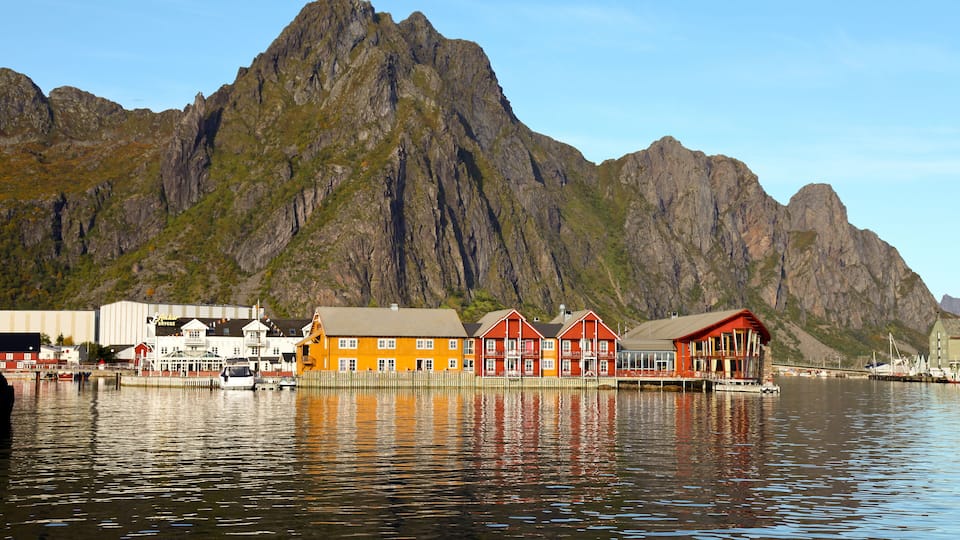 A fjord with colorful buildings and a mountain in the background.