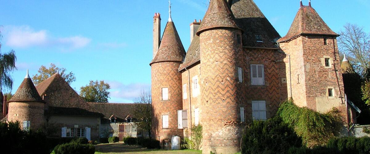 A historic castle with multiple towers and a well-maintained garden.