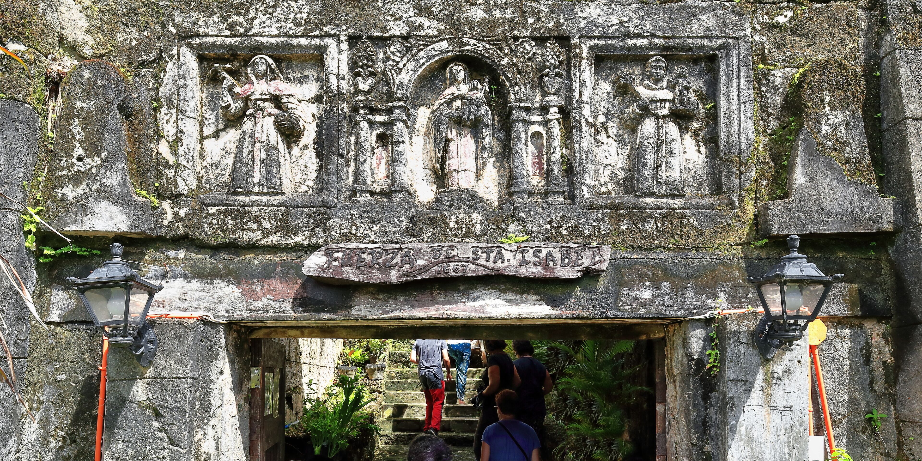 A stone archway with carvings and a sign reading "Feria de Sta. Isabel".