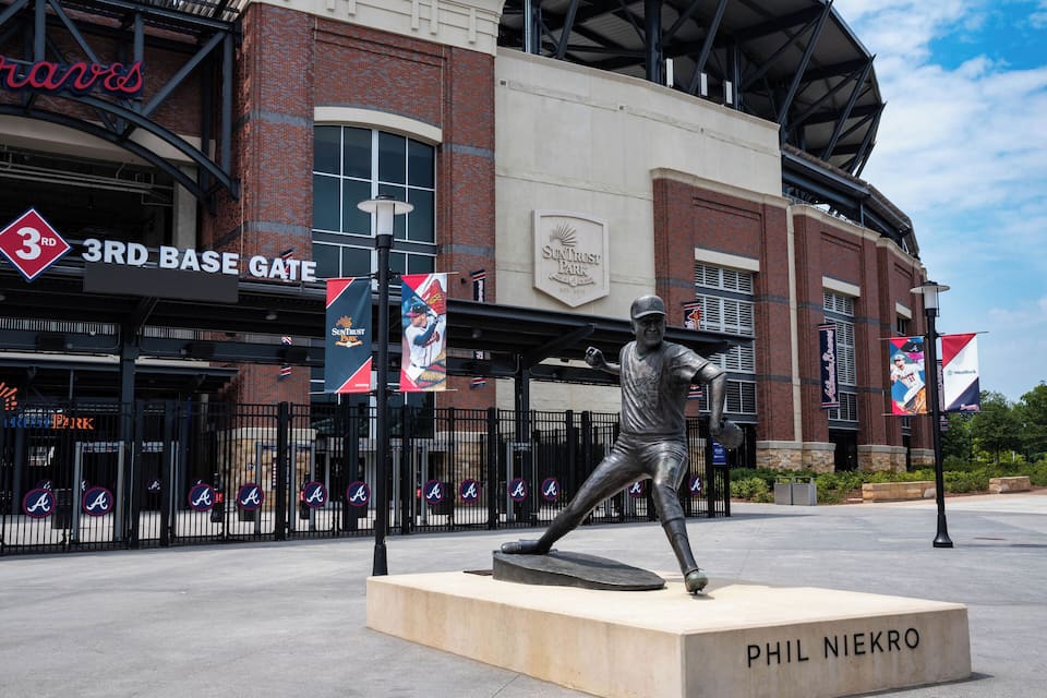 A baseball stadium with a statue of a baseball player and the name "PHIL NIEKRO" on a base.