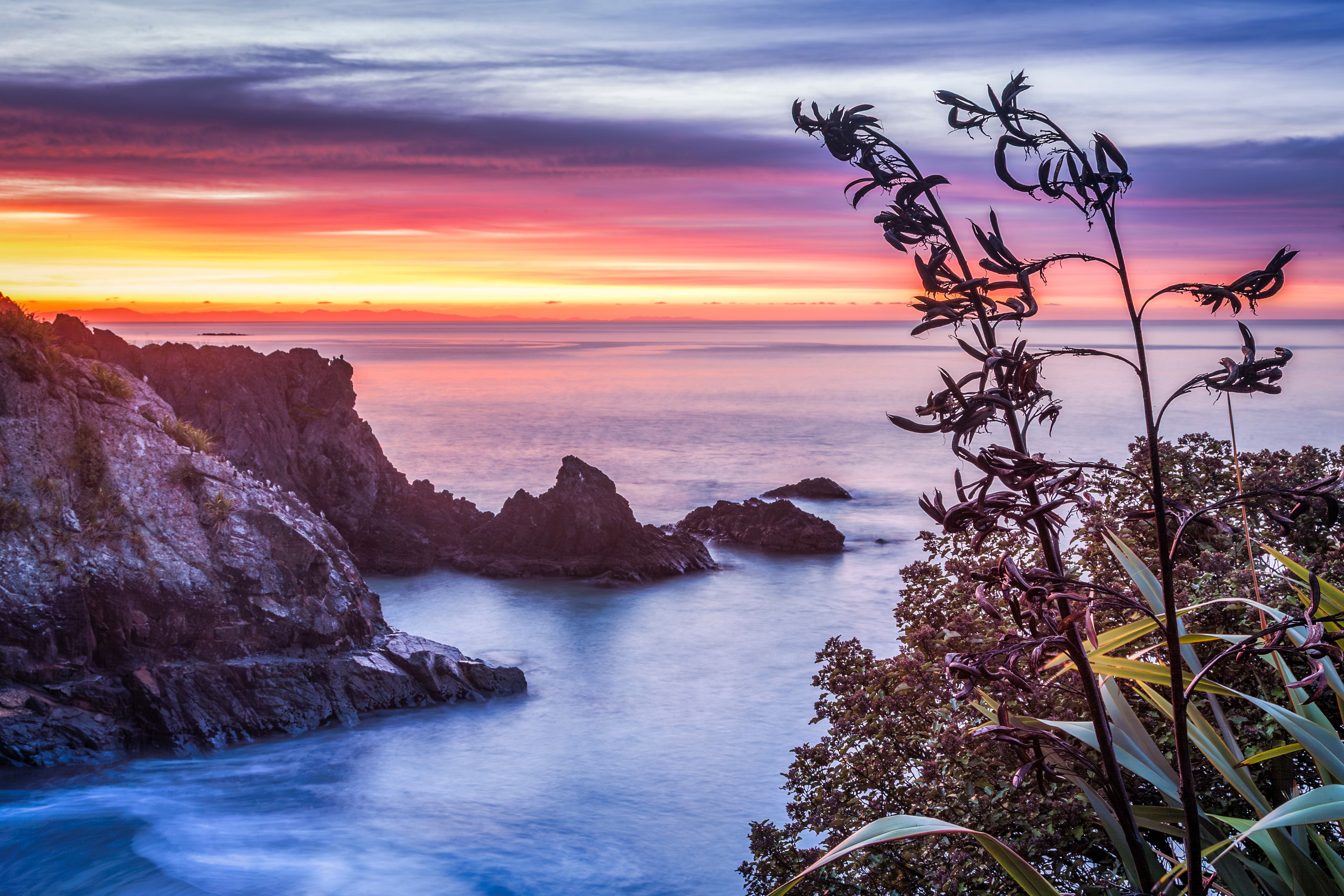 Un paysage côtier avec des falaises rocheuses et un coucher de soleil sur l’océan.