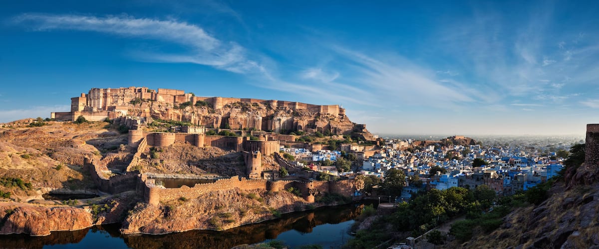 A historic fort atop a hill overlooking a town with a river at its base.