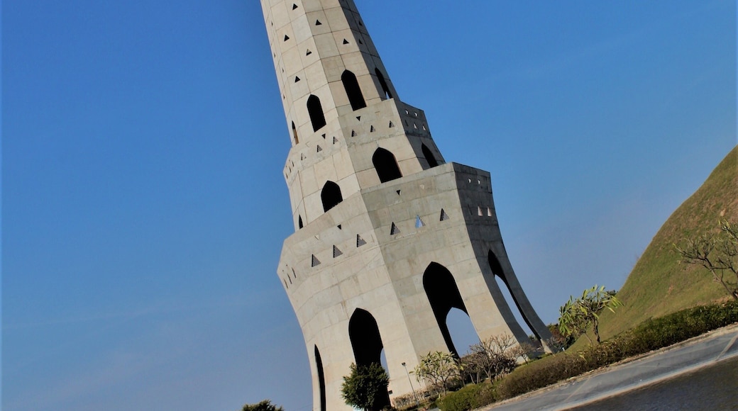 A beautiful huge tower just near a small pond standing tall in clear sky in chandigarh, india.