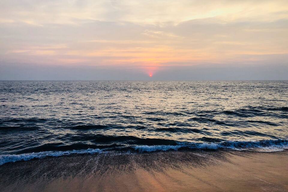 Ein Strand mit Wellen und einem Sonnenuntergang in der Ferne.