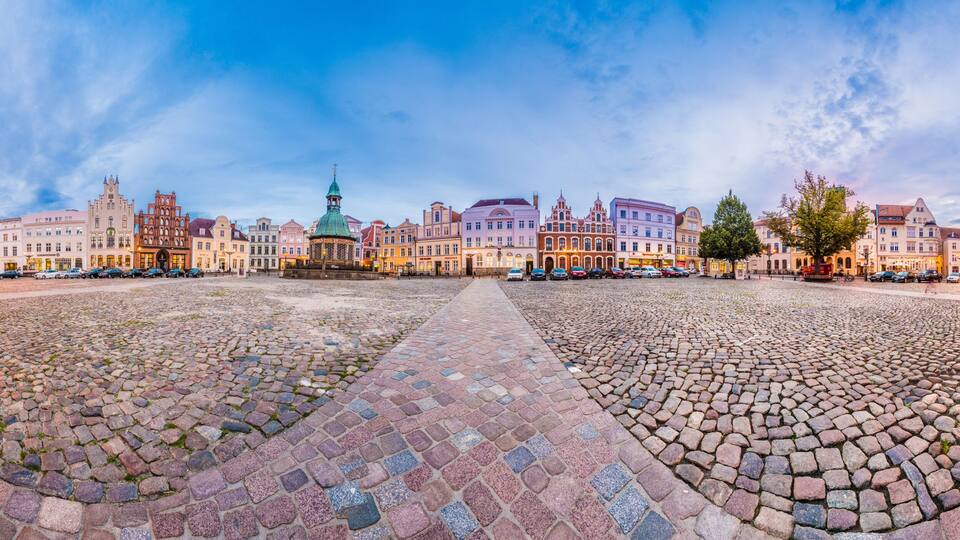 A cobblestone square with historic buildings and a prominent church steeple.