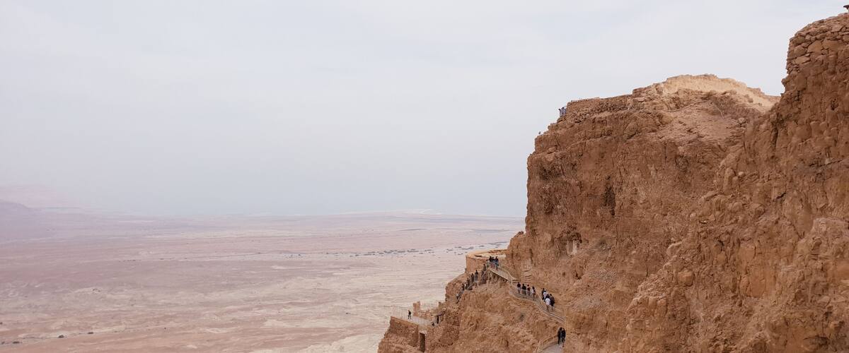A rocky cliff with a viewing platform and a vast desert landscape.