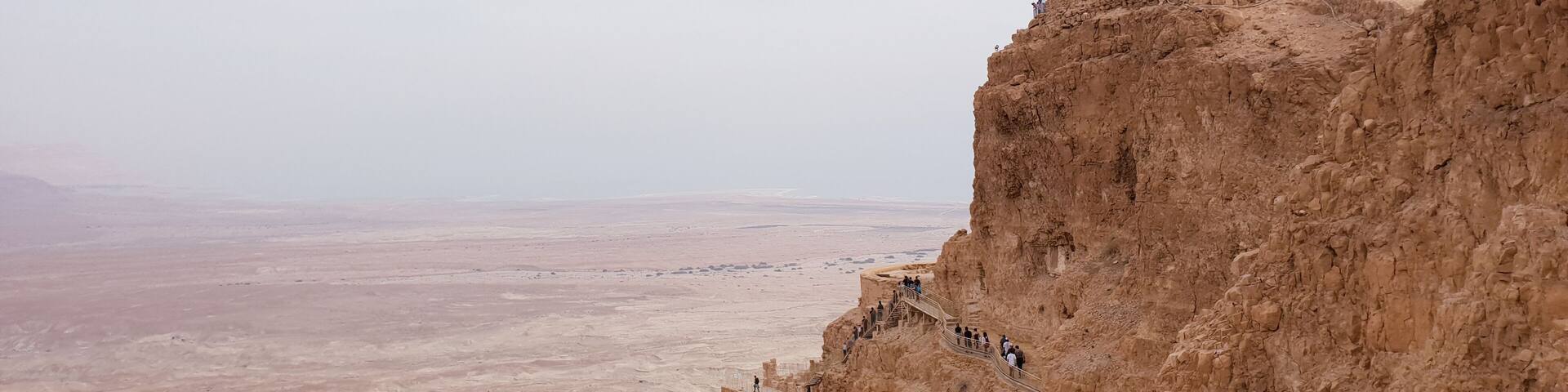 A rocky cliff with a viewing platform and a vast desert landscape.