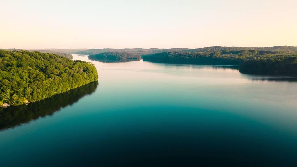 A calm lake surrounded by dense forest and hills.
