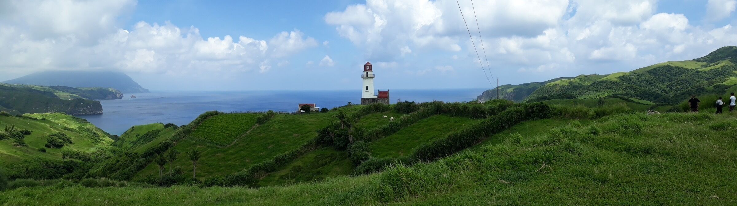 A lighthouse on a grassy hill overlooking the ocean.