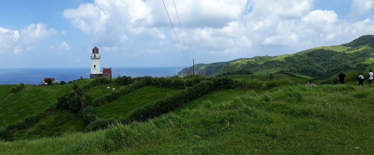 A lighthouse on a grassy hill overlooking the ocean.