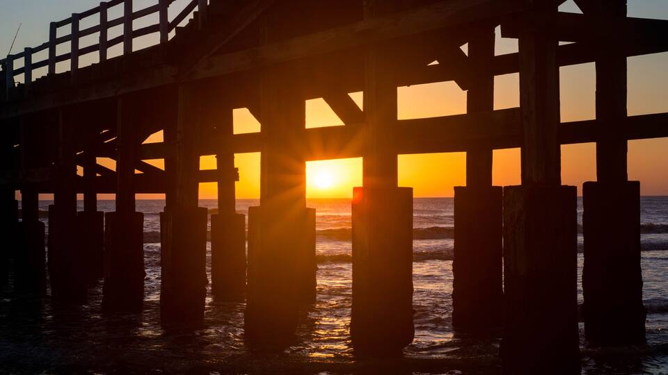 A pier with the sun setting behind it.