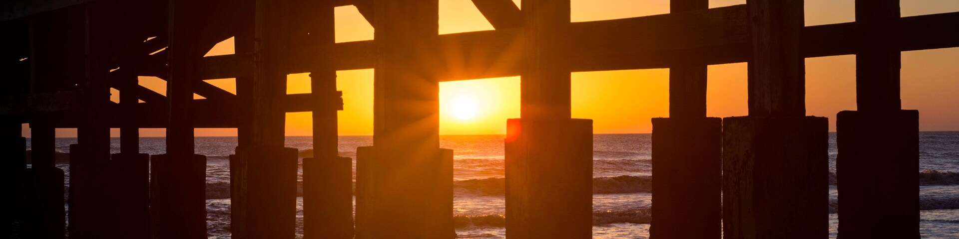 Un muelle con el sol poniéndose al fondo.