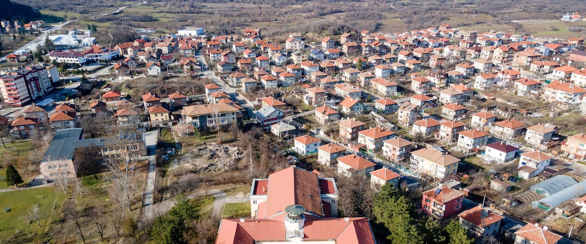 An aerial view of a residential area with a prominent historic building with a red roof in the center.