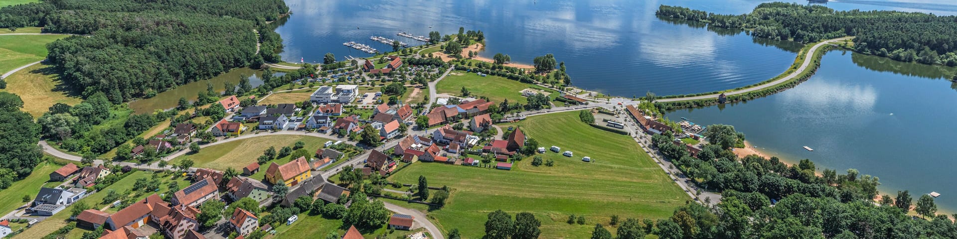 Un pueblo a orillas de un lago, con casas, muelles y cielo despejado.