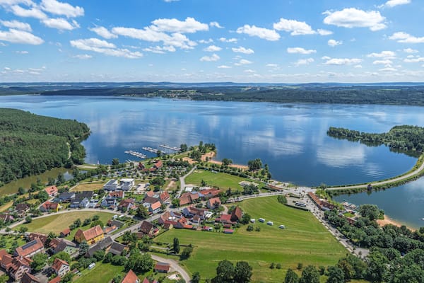 Ein Dorf am See mit Häusern, Stegen und blauem Himmel.