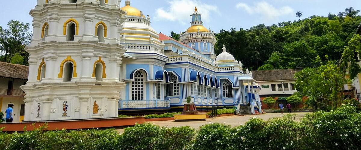 A white and blue church with multiple domes and a tall bell tower.