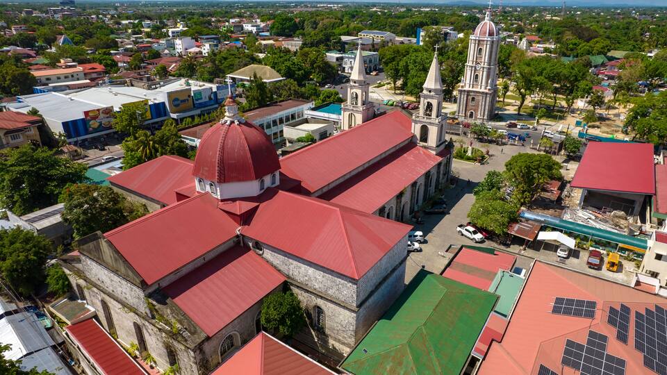 A town with a prominent church with a red dome and a bell tower, surrounded by various buildings and greenery.