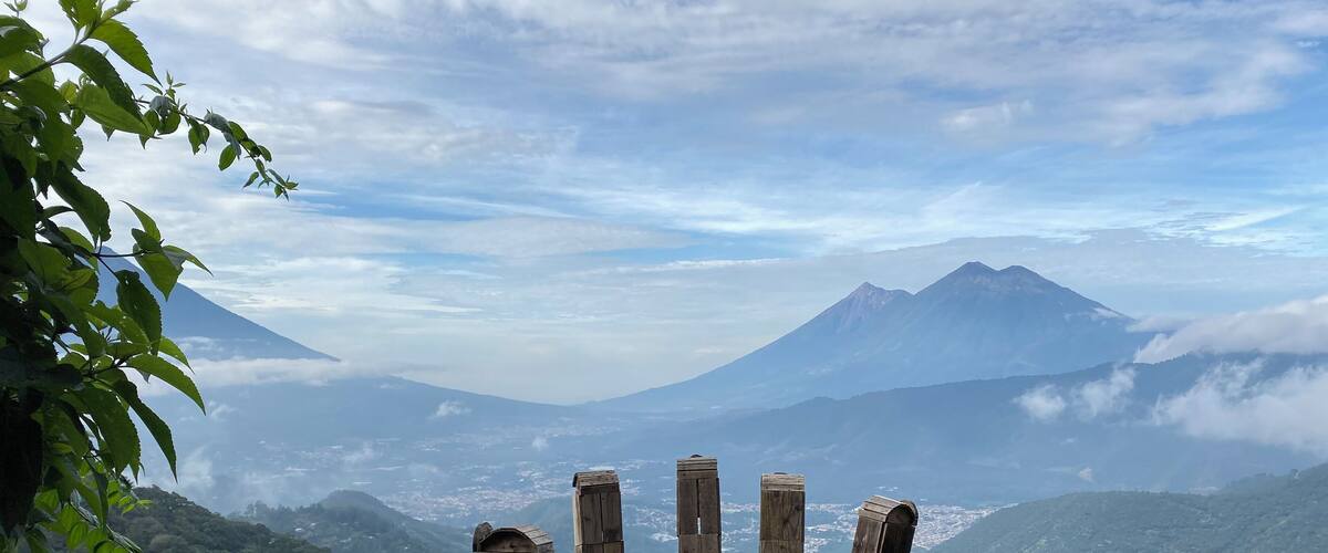 A wooden viewing platform overlooking a mountainous landscape with a prominent volcano in the distance.