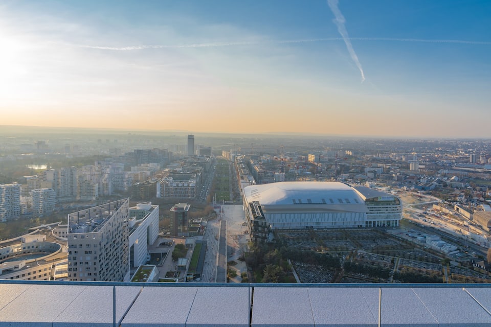 Panorama urbano con uno stadio imponente, grattacieli e cielo sereno.