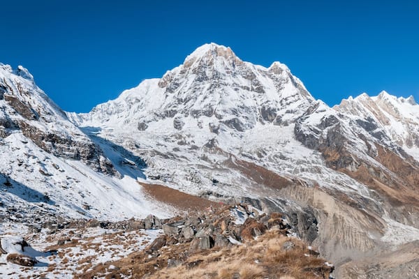 A snow-covered mountain range with rocky outcrops and a small hut.
