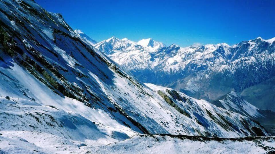 A snow-covered mountain ridge with a clear blue sky.