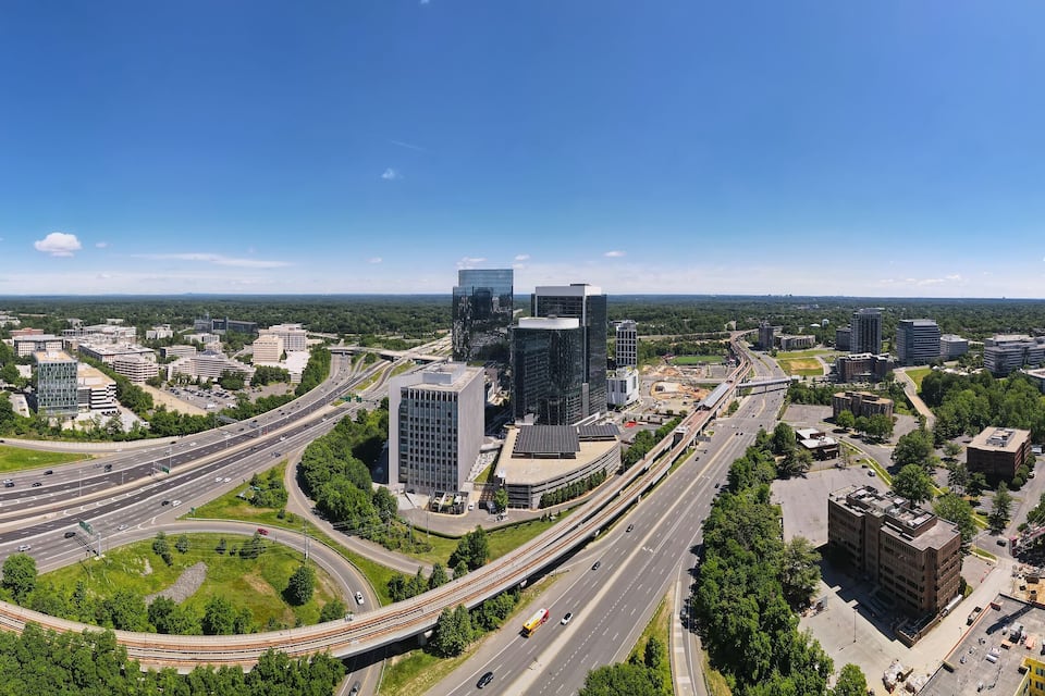 Panoramica urbana con autostrade, edifici moderni e aree verdi circostanti.
