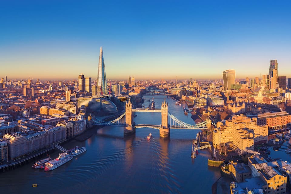 A panoramic view of a cityscape with the Tower Bridge and the Shard in the background.