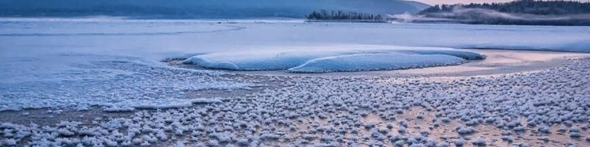 Un lago congelado con una montaña al fondo.
