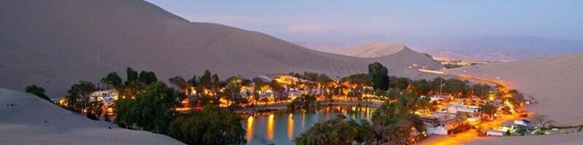 Un pueblo desértico con un lago, rodeado de dunas de arena.