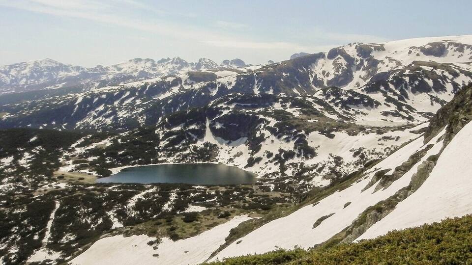 A mountainous landscape with a lake and snow-covered peaks.