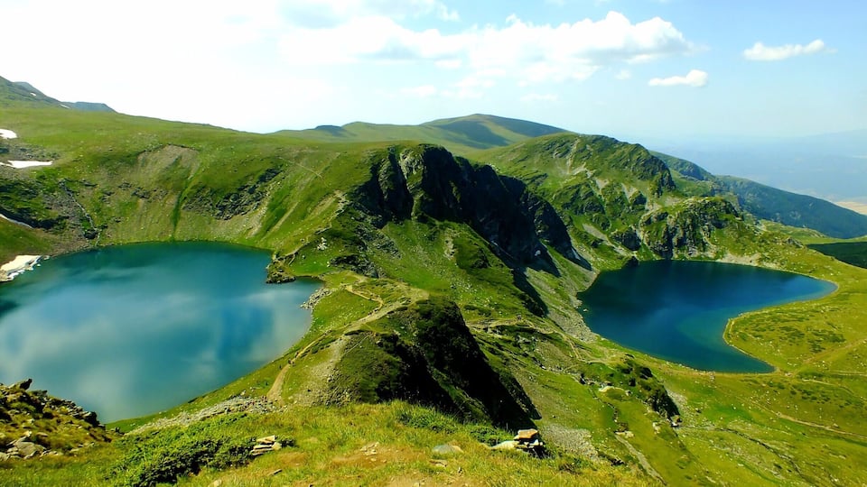 A mountainous landscape with two lakes and a hiking trail.