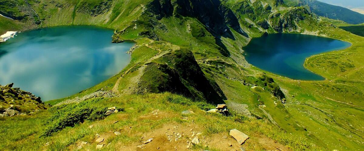A mountainous landscape with two lakes and a hiking trail.