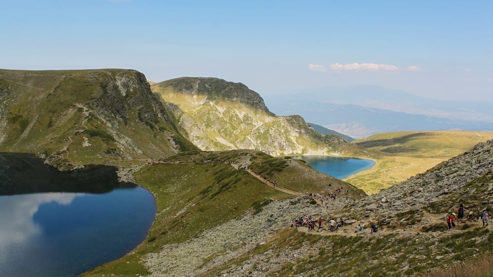 A mountainous landscape with a lake and hikers.