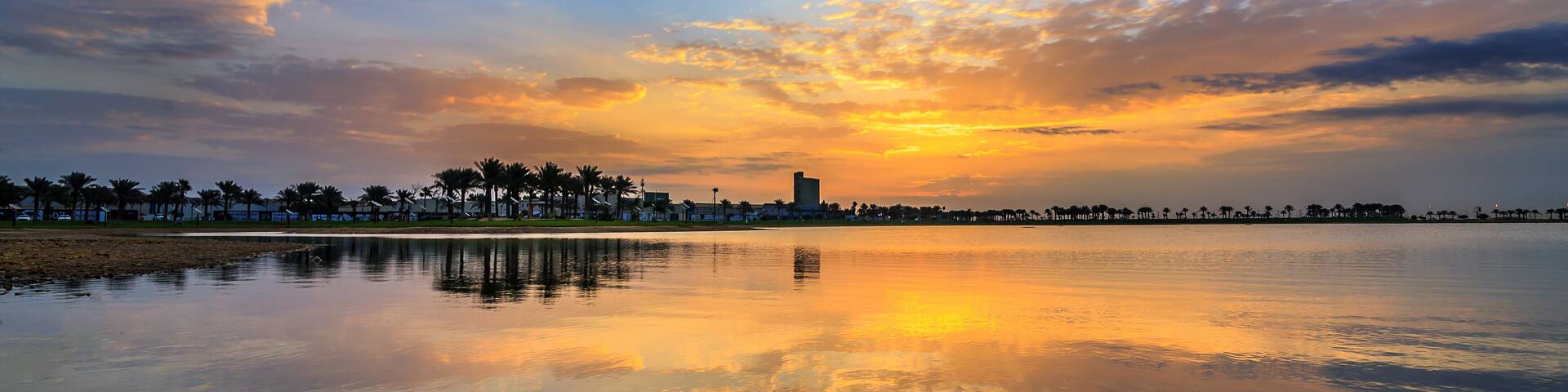A sunset over a calm body of water with a city skyline in the distance.