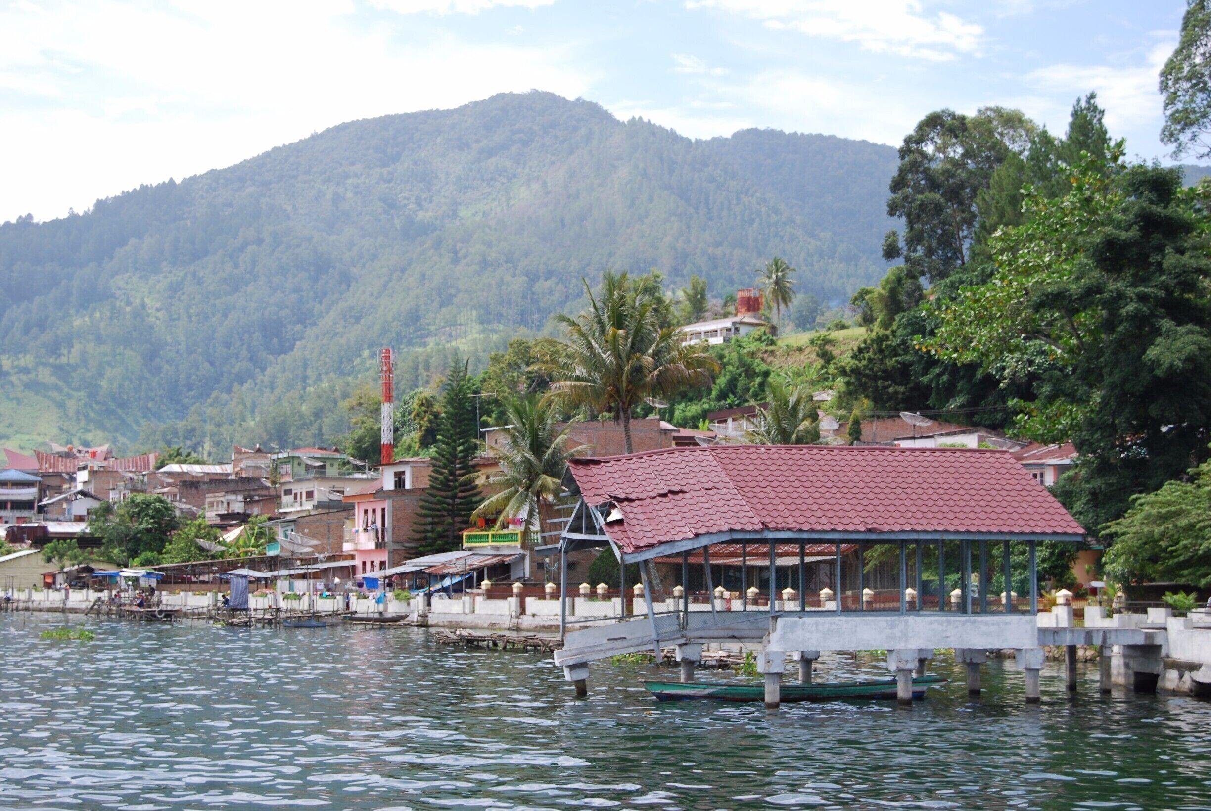 A riverside town with a bridge, boats, and a mountain backdrop.