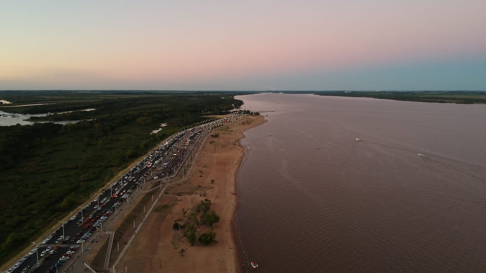 A coastal road with a long line of cars and a sandy beach.