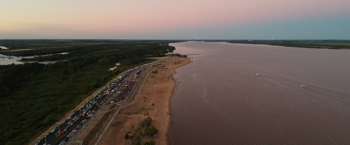 A coastal road with a long line of cars and a sandy beach.