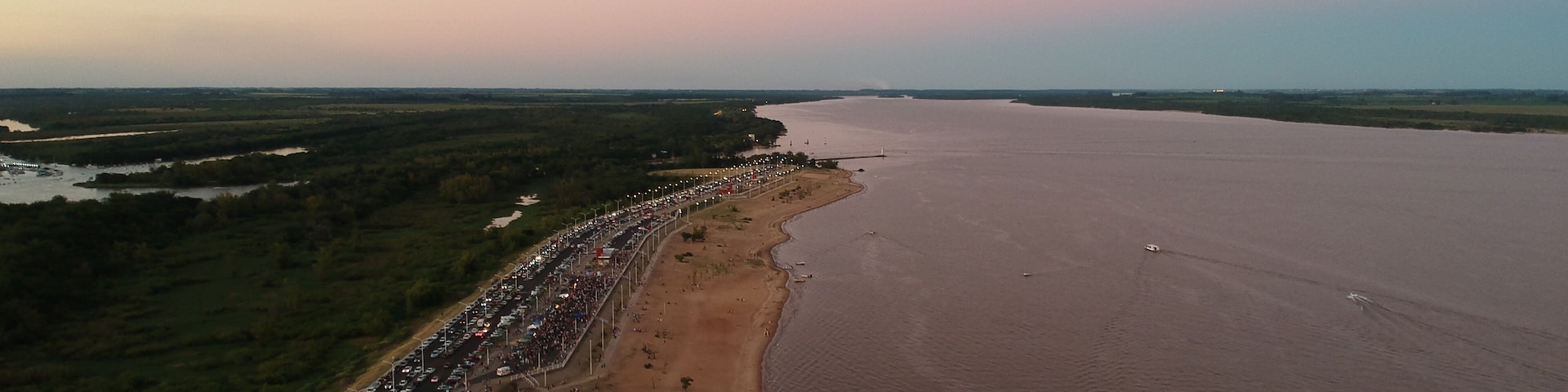 A coastal road with a long line of cars and a sandy beach.