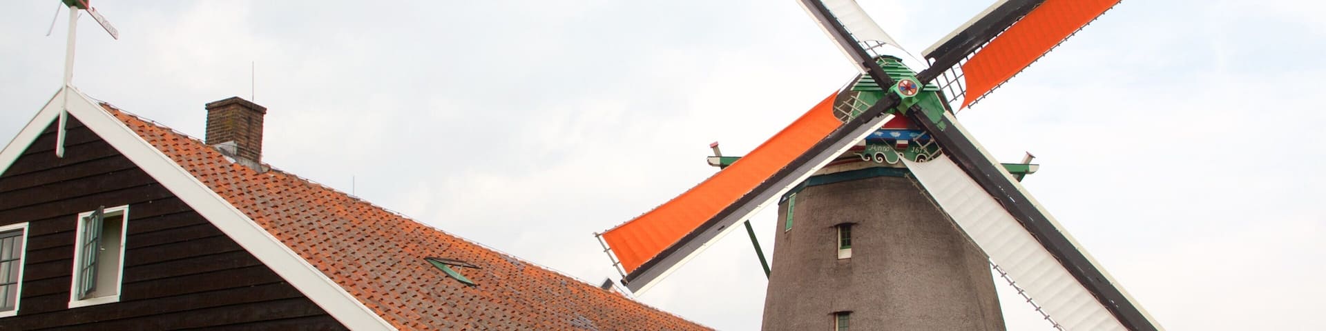 A traditional wooden house with a windmill in the background.