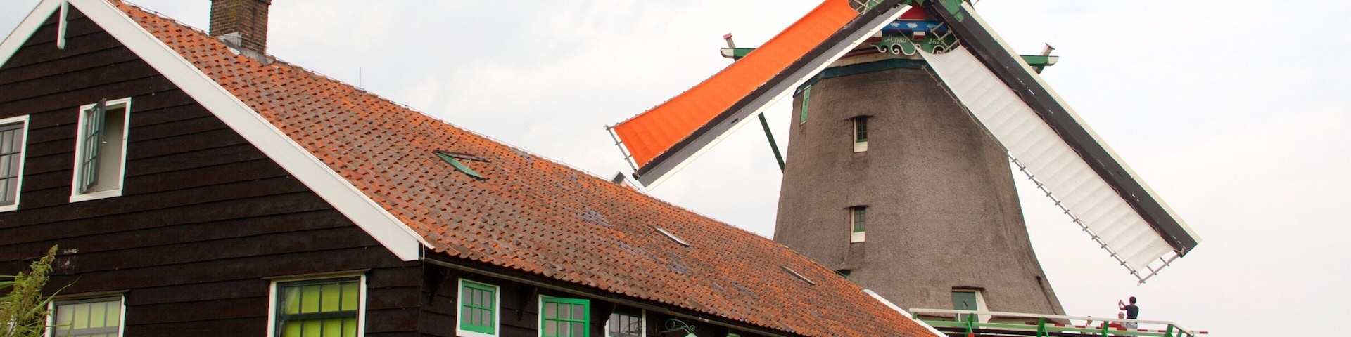 Una casa de madera tradicional con un molino de viento al fondo.