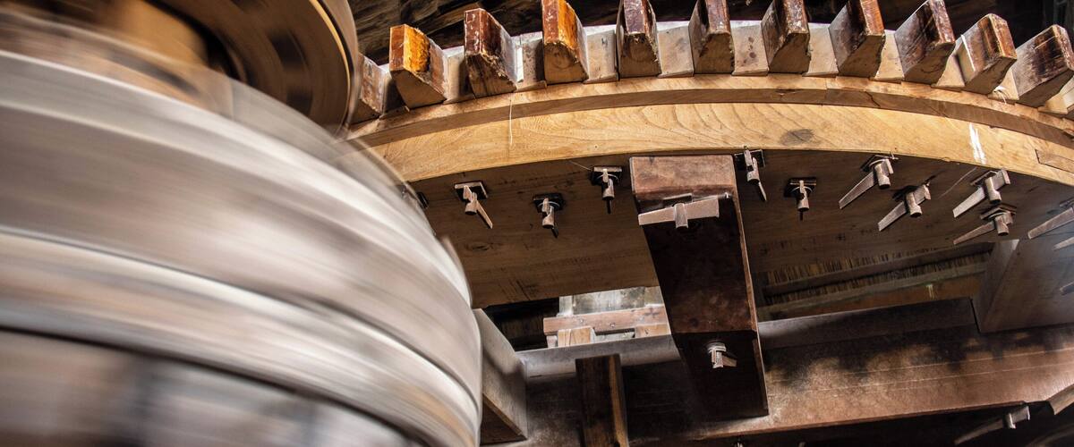 A large wooden gear mechanism with metal components and wooden planks.