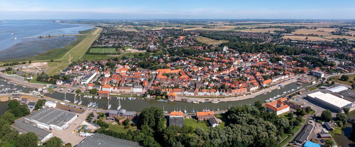 An aerial view of a town with a river, a marina, and surrounding fields.