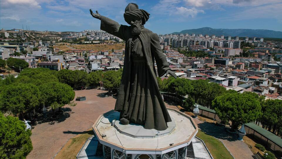 A statue of a historical figure overlooking a cityscape with mountains in the background.