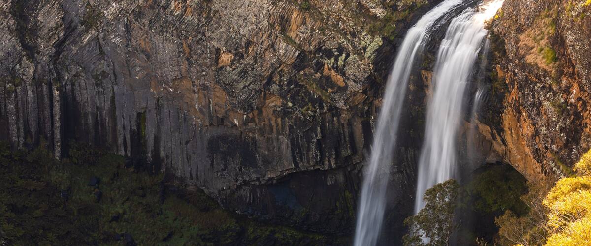 A waterfall cascading down a rocky cliff surrounded by dense forest.