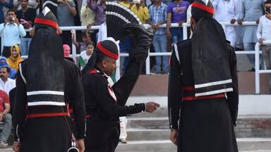 Un grupo de personal uniformado de color negro con bandas rojas y blancas, de pie en una calle con gente en el fondo.