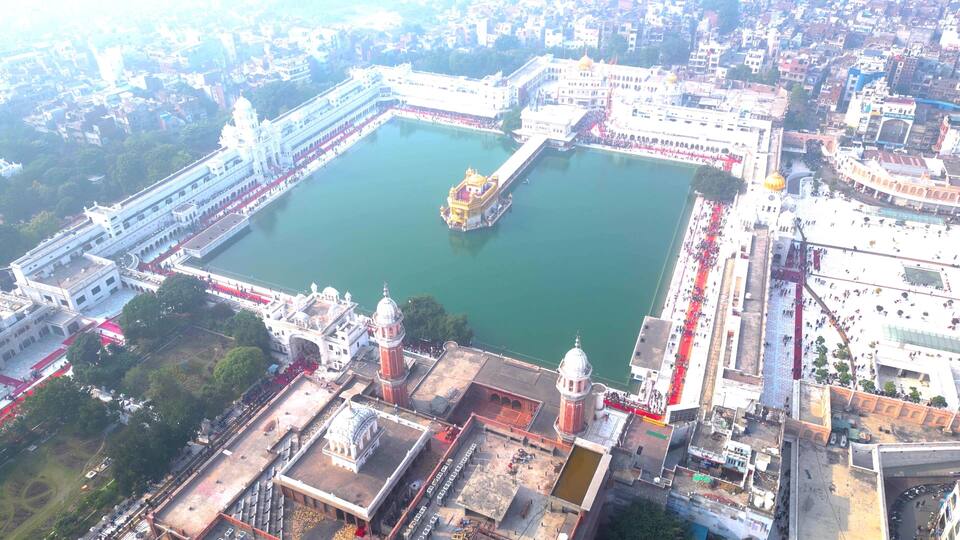A large square with a central water body, surrounded by white buildings with domes and a golden structure in the middle.