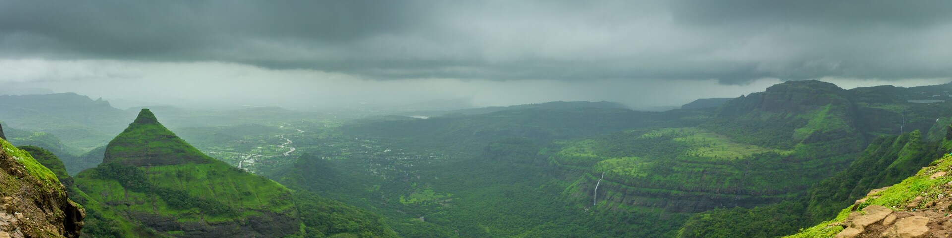 A mountainous landscape with lush green valleys and a river winding through the terrain.
